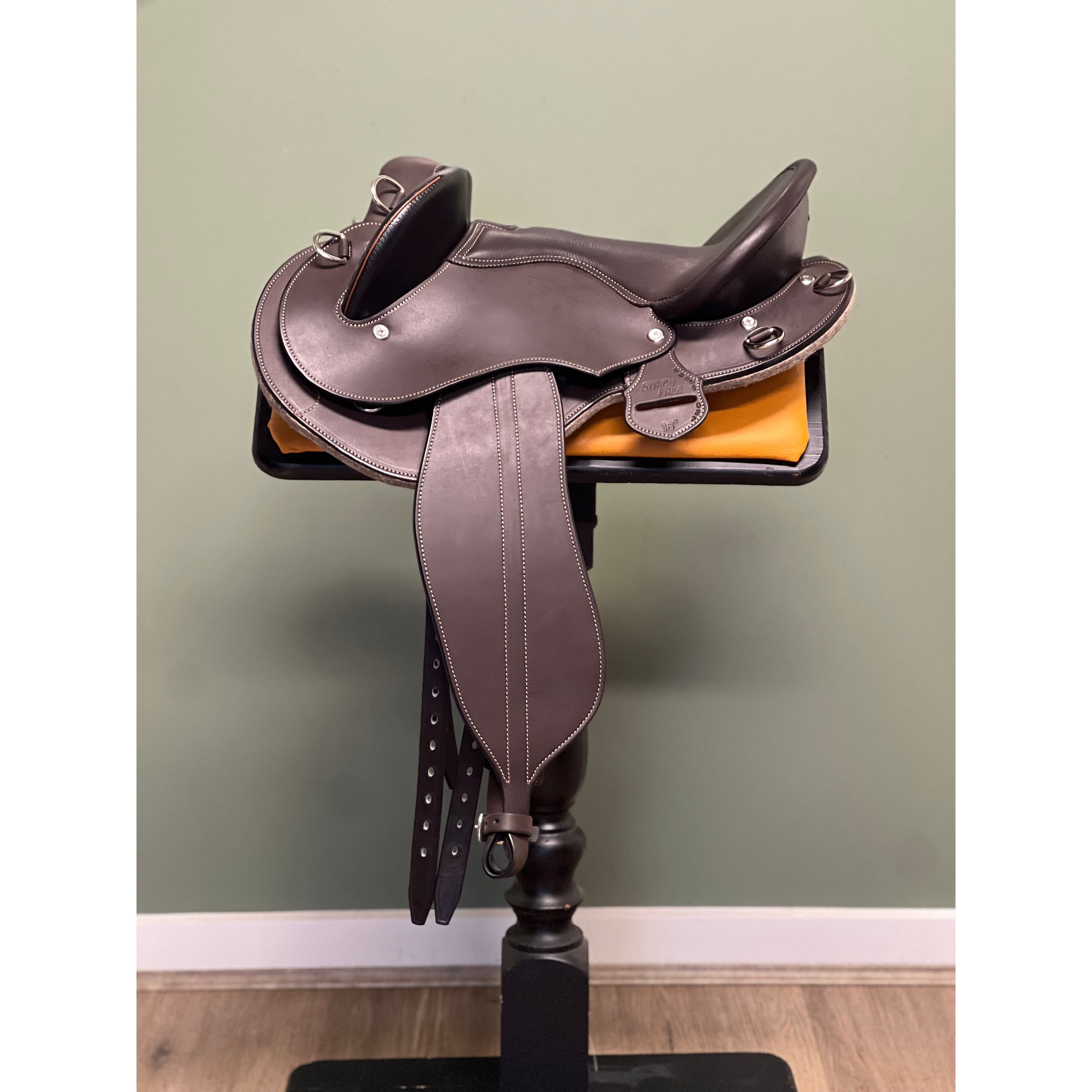 A brown StrideFree Feathertop saddle displayed on a saddle stand against a green wall, with no visible brand marking.